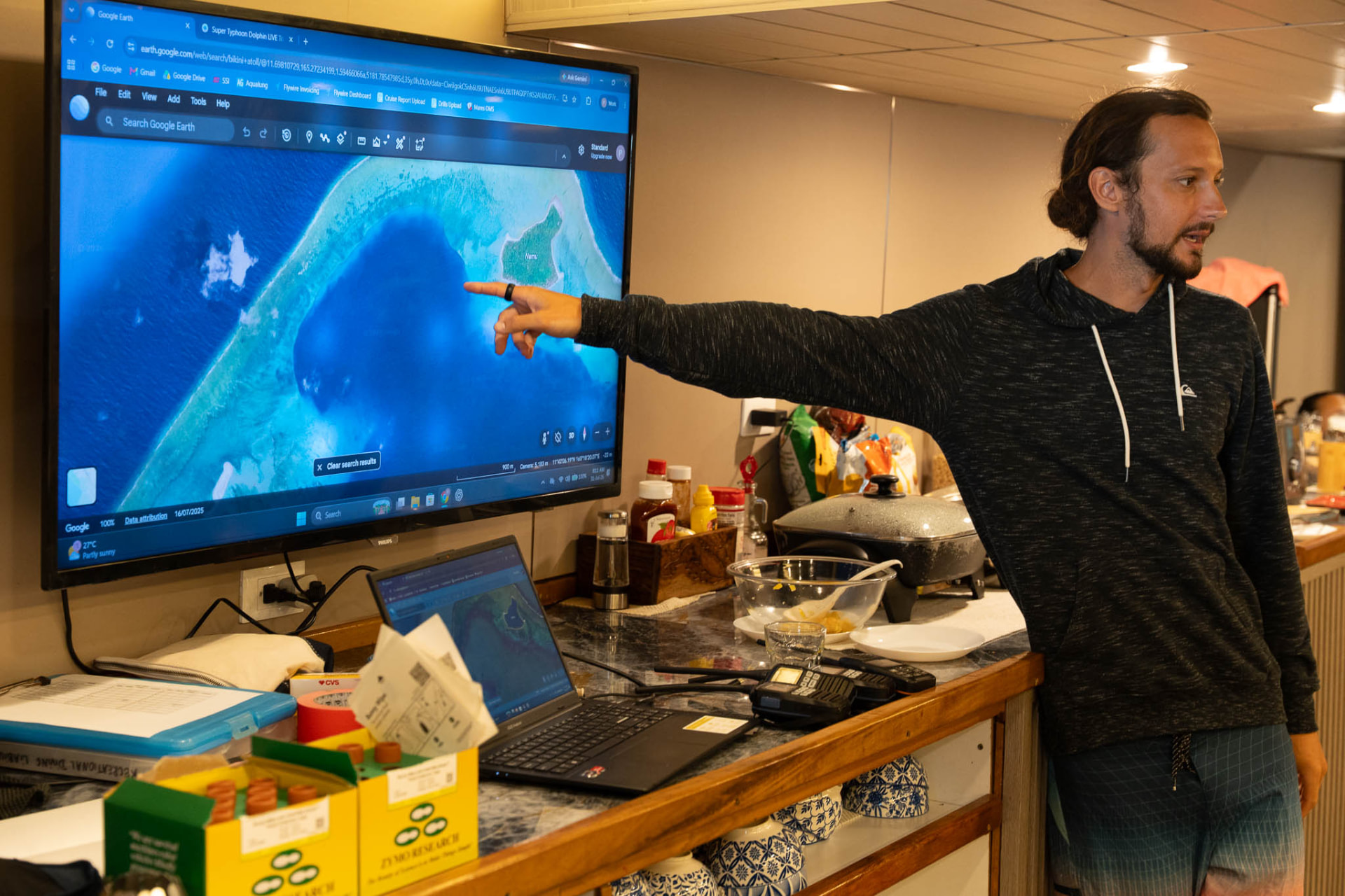 An expedition scientist briefing the team using satellite imagery of Bikini Atoll