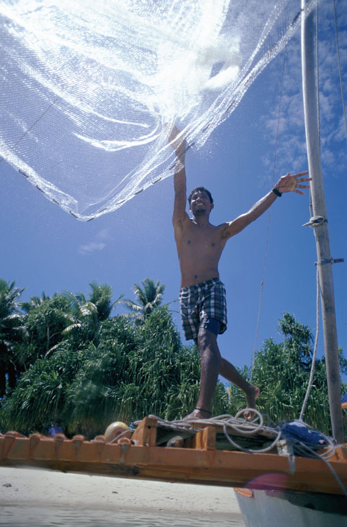 A fisherman casting a net from a small boat off Jaluit Atoll