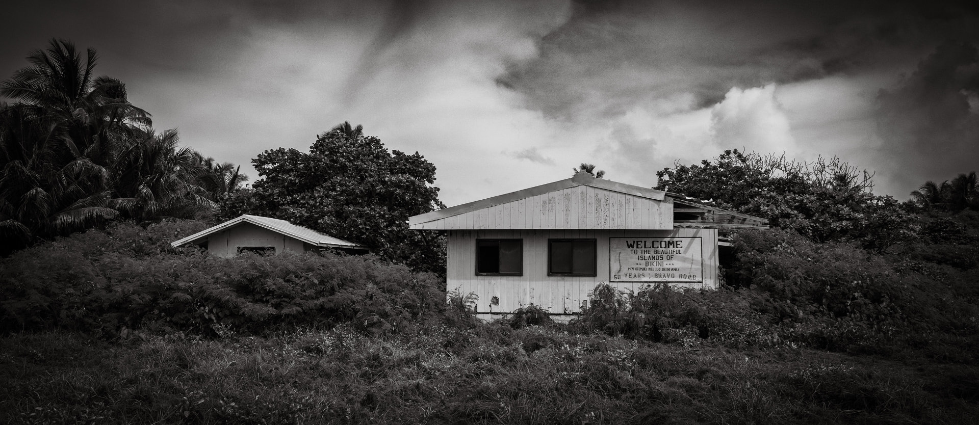 Abandoned building on Bikini Island with a faded welcome sign marking 50 years since the Bravo bomb