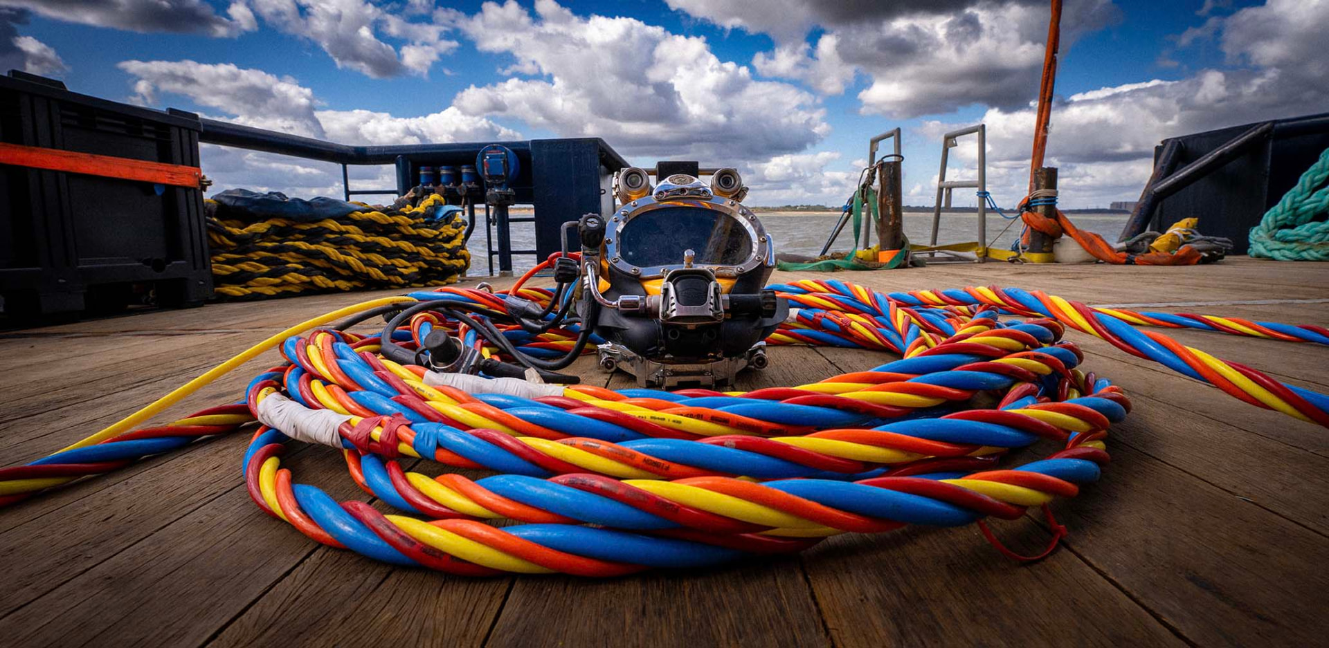 Colourful diving umbilicals coiled around a helmet on the work deck