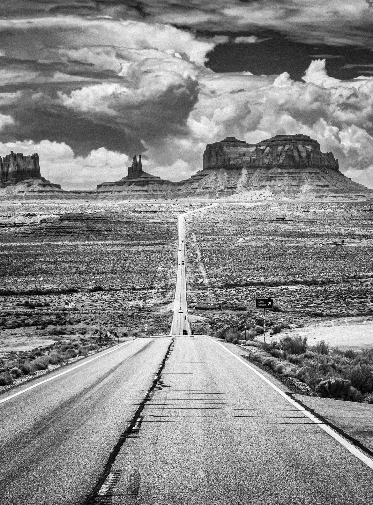 A straight desert road leading towards the buttes of Monument Valley under storm clouds