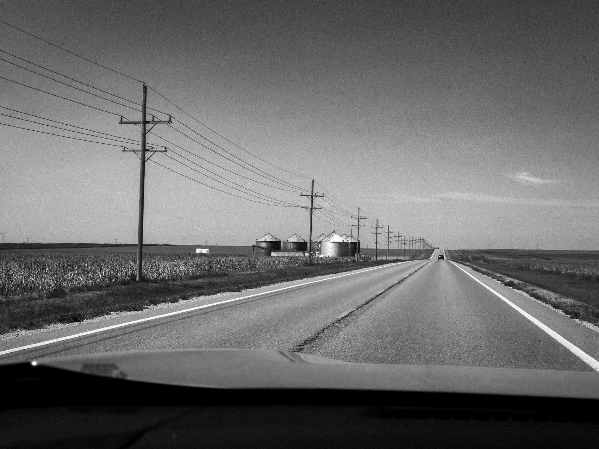 A long straight Kansas highway heading west beneath a wide sky